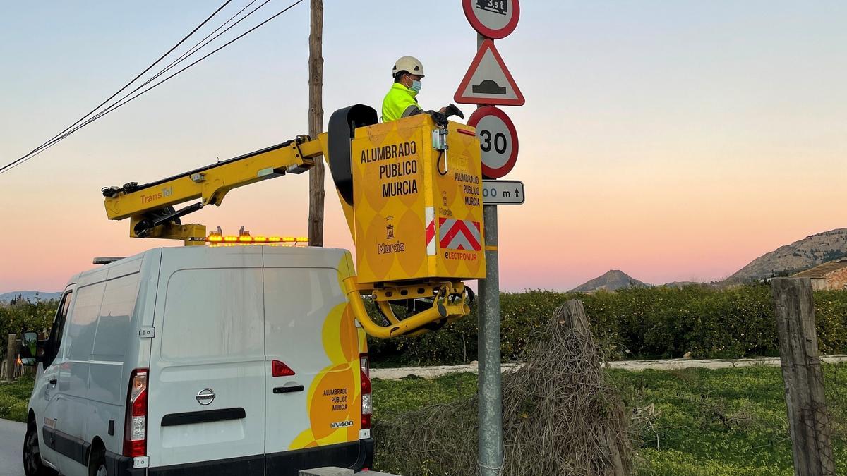 Un operario del Ayuntamiento de Murcia cambiando la luz de una farola.