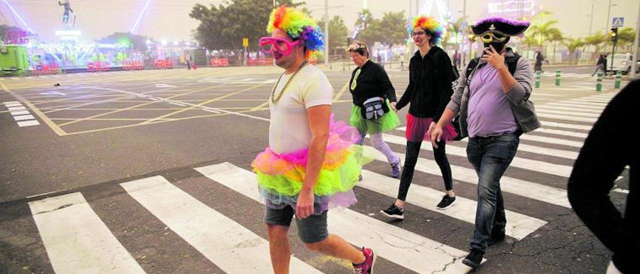 Varias personas disfrazadas pasean bajo la densa capa de calima para acudir al Carnaval de Día de Santa Cruz el 23 de febrero.