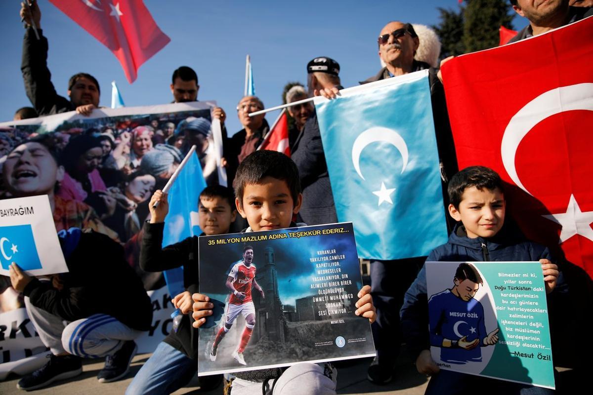 Ethnic Uighur boys hold placards with the images of English soccer club Arsenal’s midfielder Mesut Ozil during a protest against China in Istanbul, Turkey December 14, 2019. The placard reads: Thank you, Mesut Ozil, on behalf of 35 million oppressed.  REUTERS/Kemal Aslan NO RESALES. NO ARCHIVES