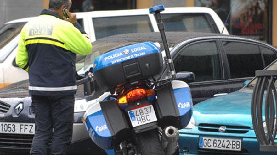 Un policía local, ayer, habla por teléfono junto a su motocicleta. i QUESADA