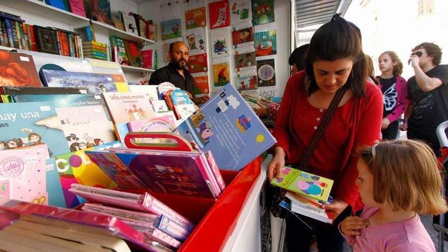 Una mujer muestra a una pequeña un libro centrado en un personaje infantil.