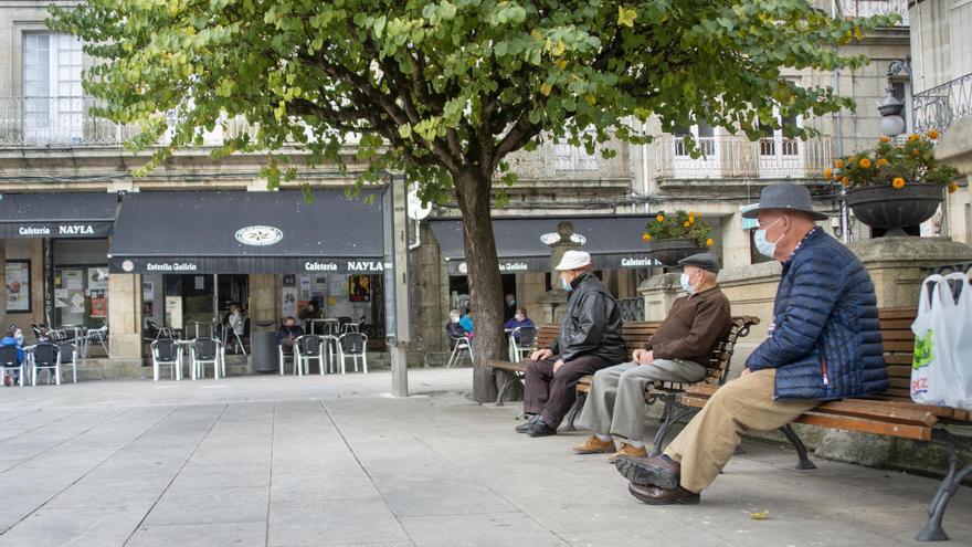 Tres hombres con mascarilla en una plaza de Carballiño. // Carlos Peteiro