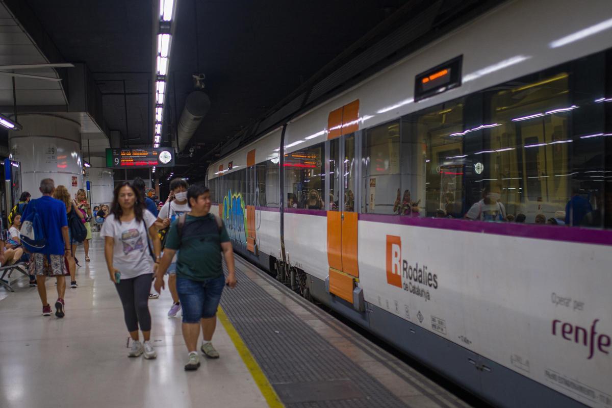 Viatgers al costat d'un tren de Renfe