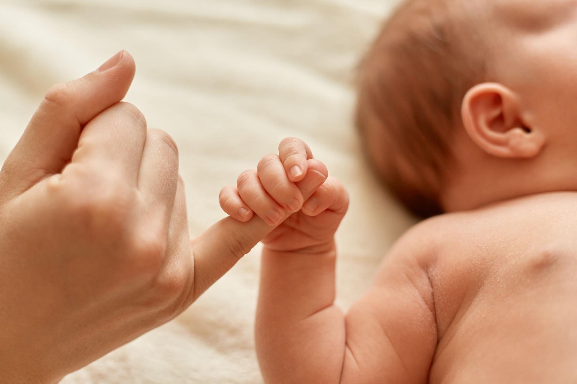 Un bebé agarrando el dedo de un adulto