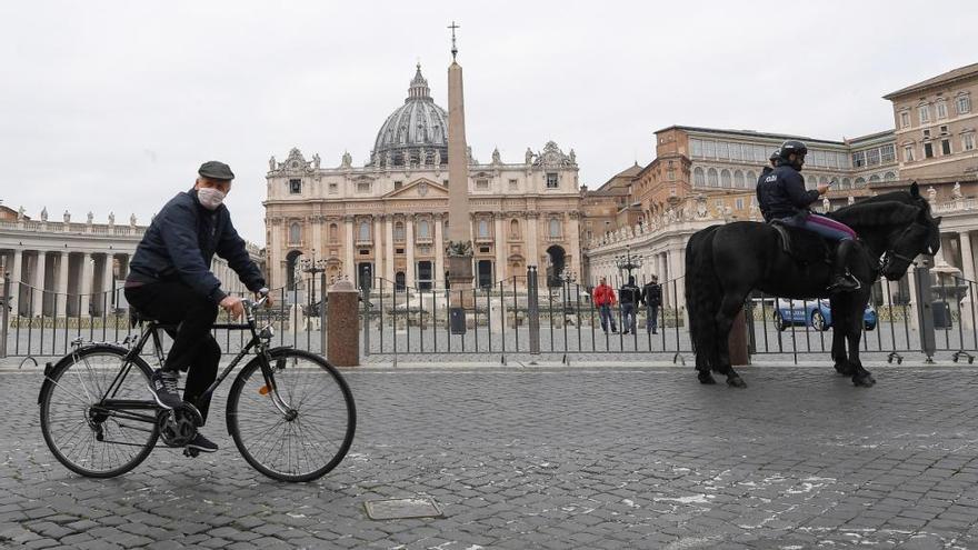 Un ciclista, protegido con una mascarilla, pasa ante una plaza de San Pedro desierta, ayer en Roma.