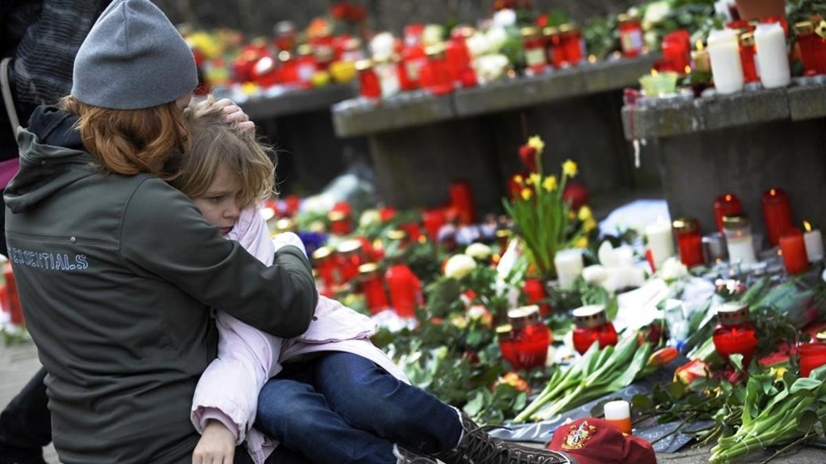 Un mujer reconforta a un niño junto a las velas y flores dejadas en la escuela Albertville, tras el tiroteo, en Winnenden (Alemania), el 12 de marzo del 2009.