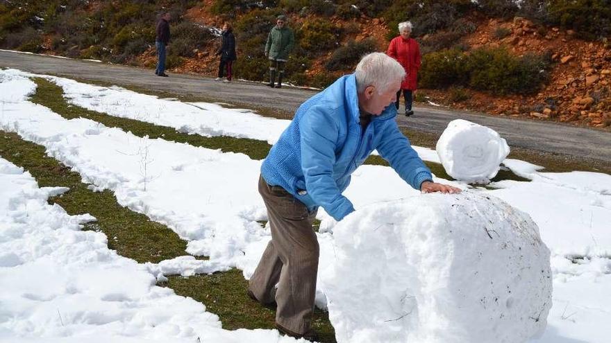 Sobre estas líneas un grupo de jubilados se entretiene con la nieve en Doney; a la derecha una persona pasa por una calle de Escuredo que amaneció con carámbanos de hielo