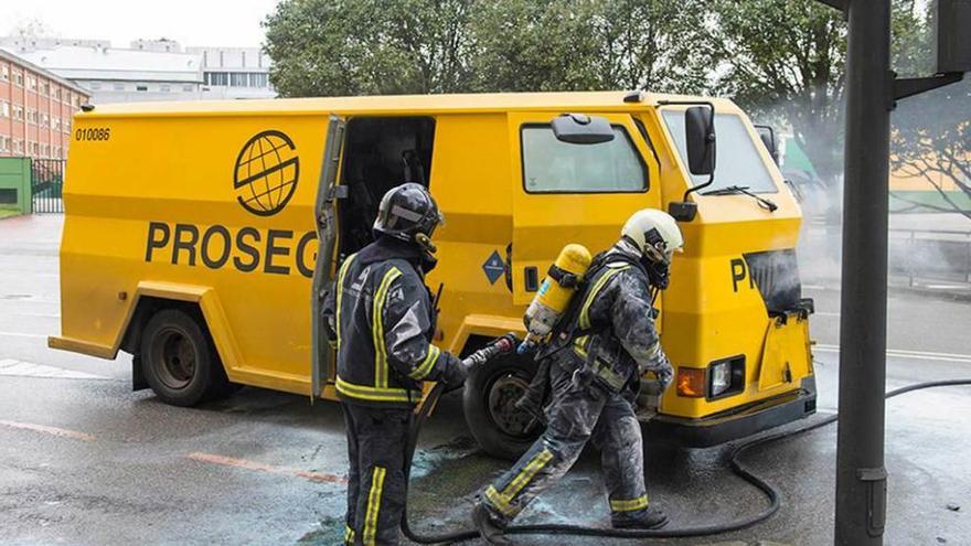 Dos bomberos, el pasado viernes, durante la extinción de un incendio originado en un furgón blindado, en la calle Fernando Morán, en Avilés.