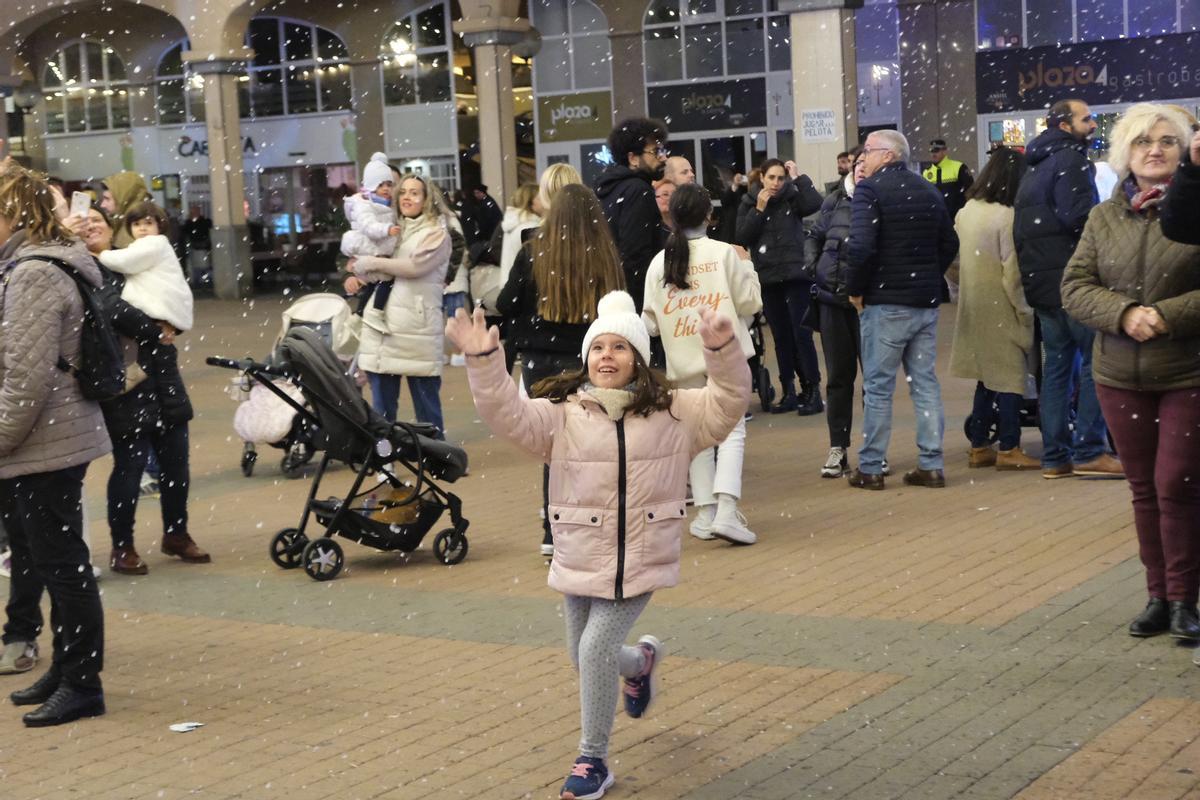 Una niña cazando los copos de nieve artificial que lanzaba el cañón en la Plaza Mayor.