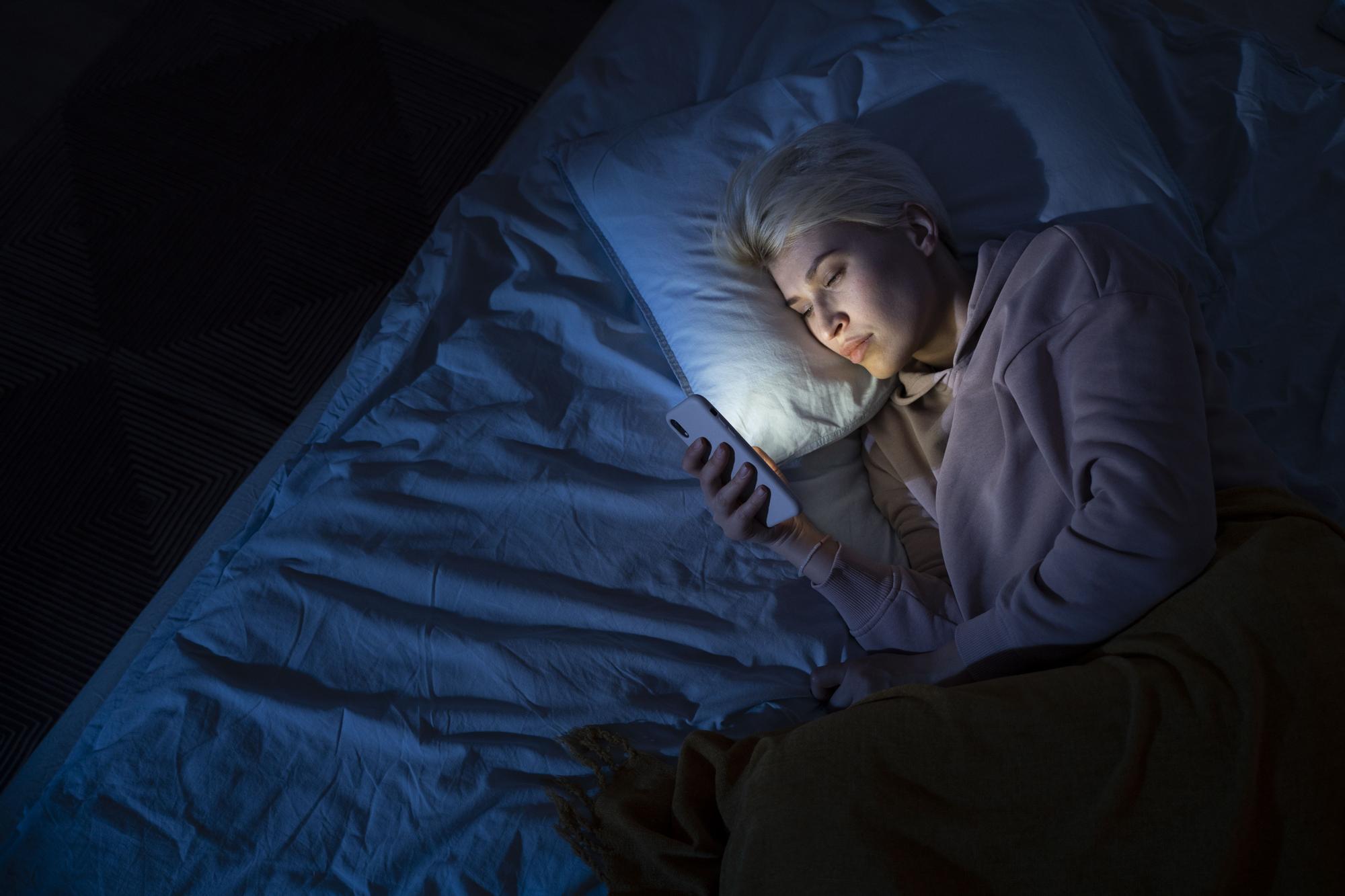 Una chica usando el móvil en la cama