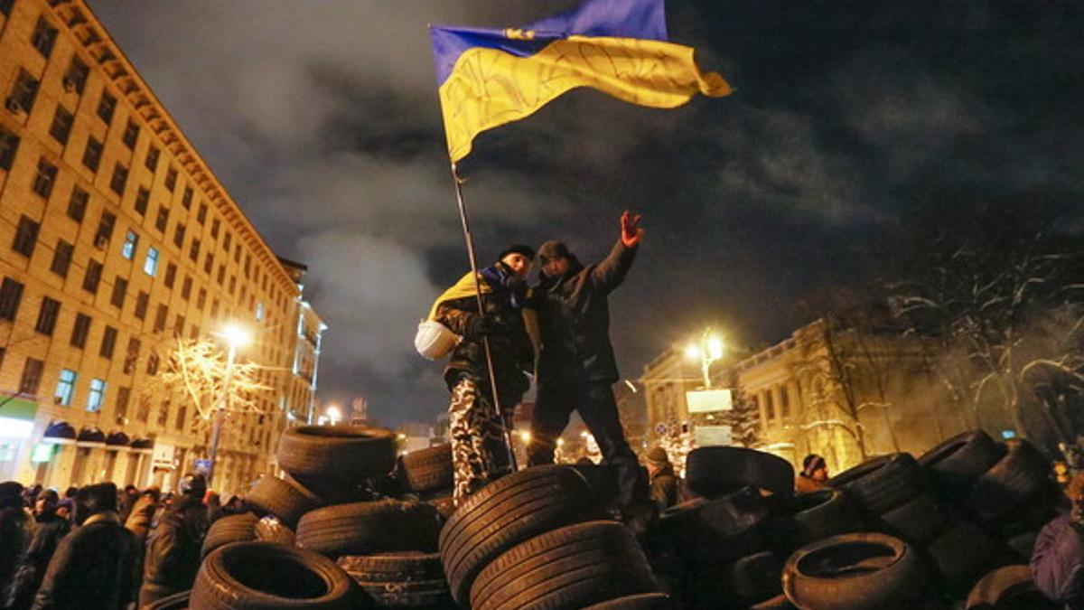 Dos manifestantes con una bandera de Ucrania sobre una barricada, en el centro de Kiev.