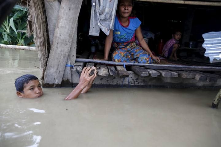 A flood victim sticks his head out of the water at his home in a flooded village outside Zalun Township, Irrawaddy Delta