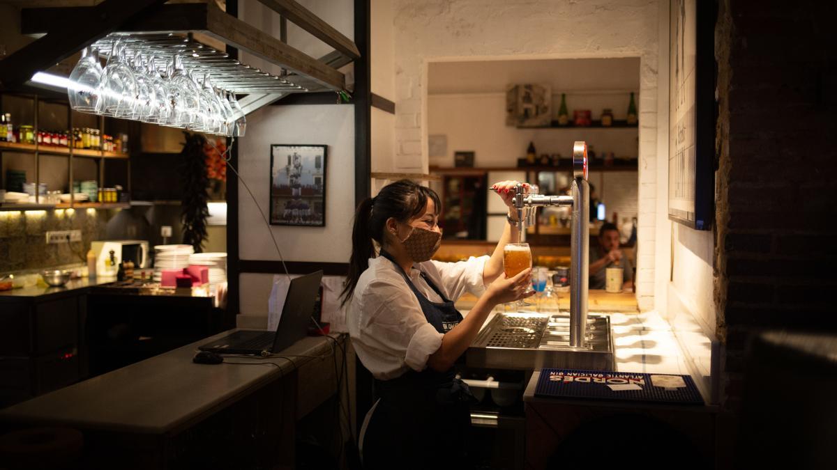 Una camarera sirve una cerveza en el interior de un bar.