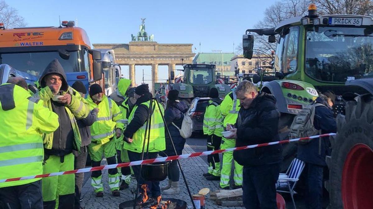 Un grupo de agricultores se calienta frente a la Puerta de Brandenburgo.