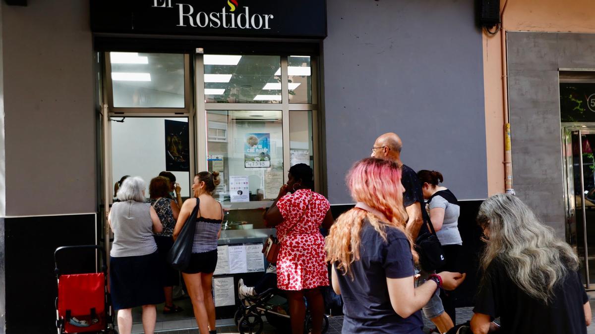 Varias personas de diferentes edades hacen cola para comprar en una casa de comidas de València, esta semana.