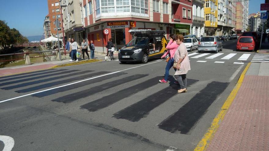 Dos mujeres cruzan la calle, una hablando por el móvil.