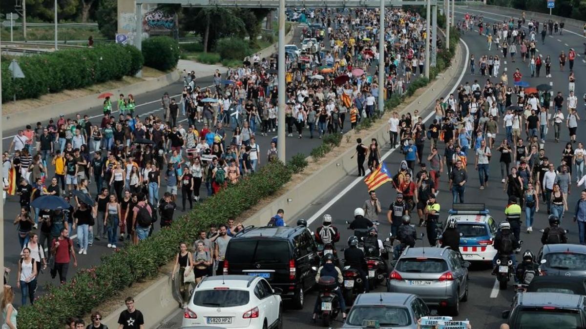 Viajeros caminan por la autopista camino del aeropuerto de El Prat.