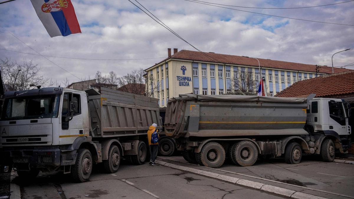 Un vianant passa entre dos camions col·locats a manera de barricada a Mitrovica, aquest dimecres