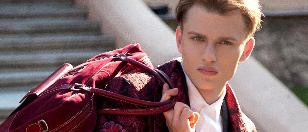 El modelo Igor Buriak luce un batín de seda labrada con motivos florales en realce, color fresa, frambuesa y berenjena. El bolso, en los mismos tonos frambuesa realizado en piel, es de la marca Abraham Zambrana.