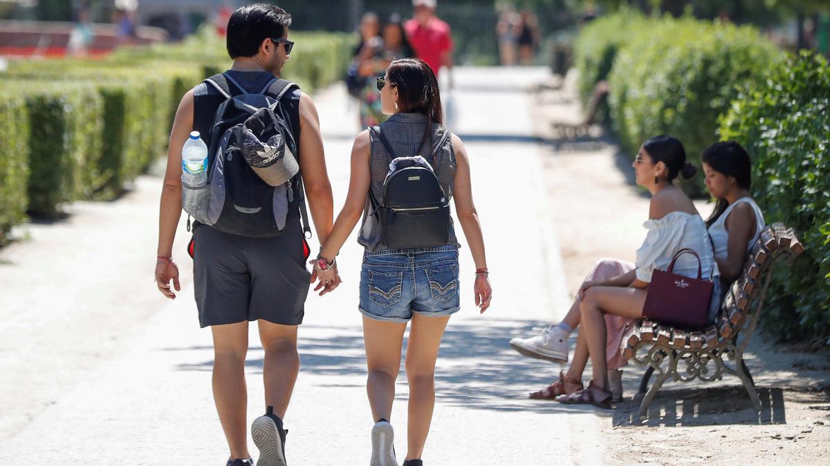 Una pareja de jóvenes paseando en un parque.