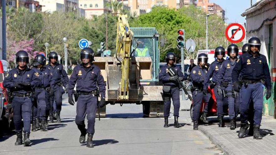 Agentes de la Policía Nacional escoltan una maquina excavadora esta mañana en el barrio del Cabanyal de Valencia, donde han continuado los derribos de viviendas.