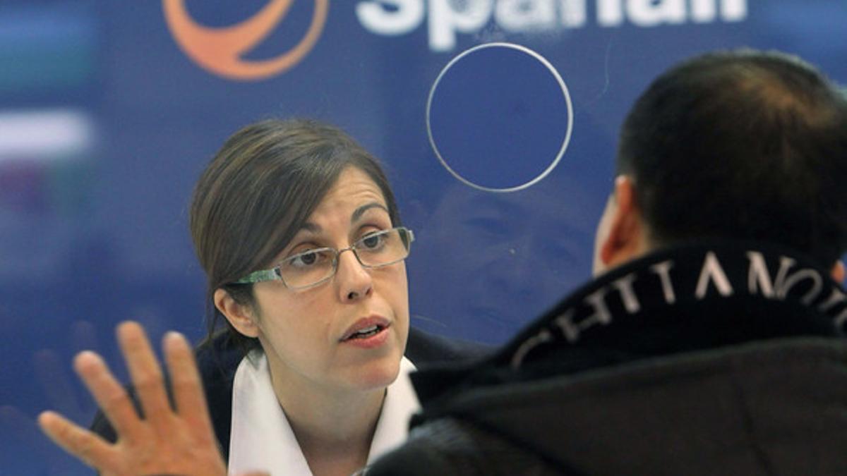 Una trabajadora de Spanair atiende a un pasajero afectado por el cese de la aerolínea, el sábado, en Barajas.