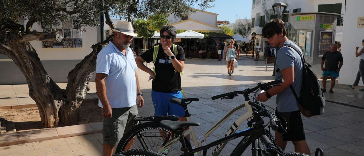 Unos vecinos de Formentera se interesan por una bicicleta expuesta en la plaza.