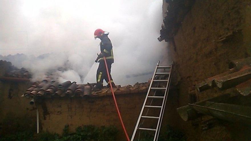 Un bombero trata de sofocar el incendio en la vivienda de Villar de Fallaves.