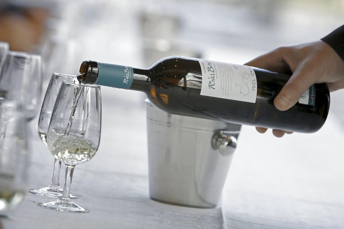 Una persona sirviendo vino blanco en una copa.