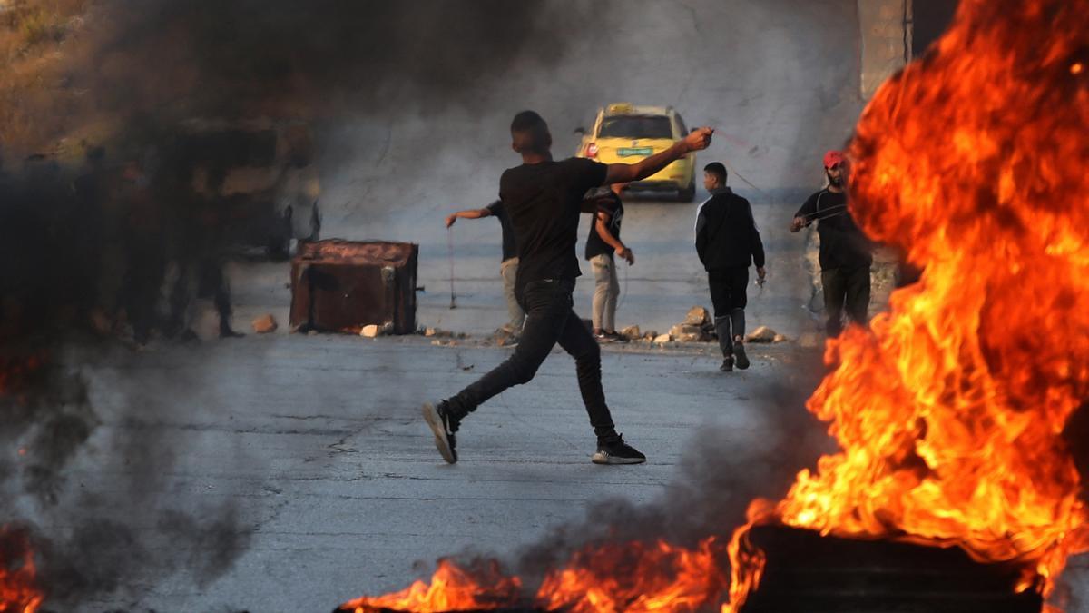 Un manifestante palestino lanza piedras contra los israelies