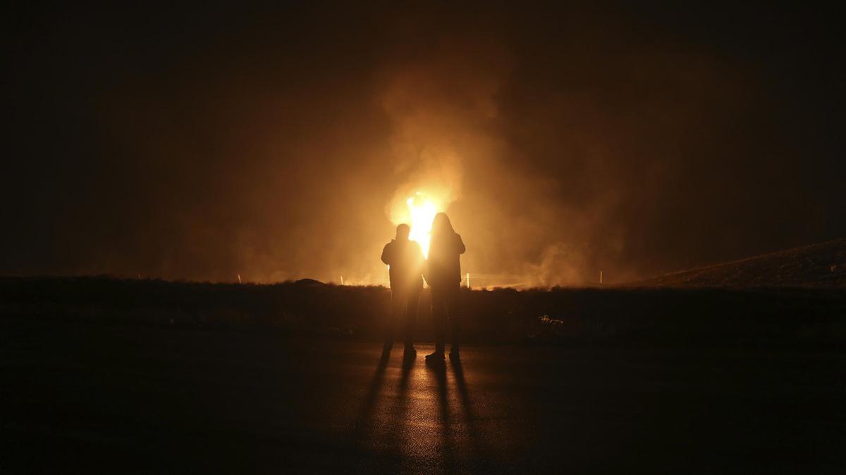 Dos hombres miran las llamas tras la explosión de un gasoducto en las afueras de la ciudad de Boroujen, Irán.
