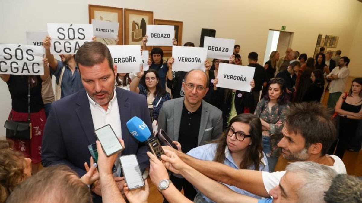 El conselleiro de Cultura, José López Campos, interviene en la inauguración de la exposición 'Illa Ignorada' ante manifestantes en protesta por la elección de Eva López Tarrío como nueva directora del CGAC.