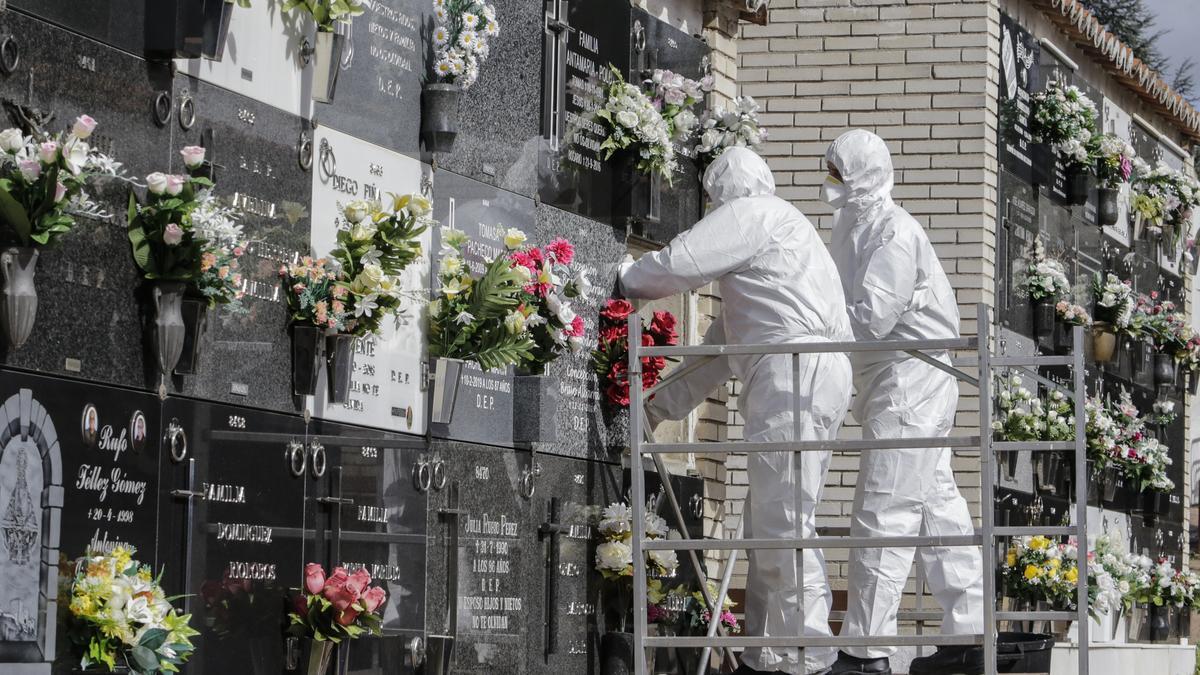 Trabajadores de una funeraria con epis colocan una lápida en el cementerio de Cáceres. / FRANCIS VILLEGAS