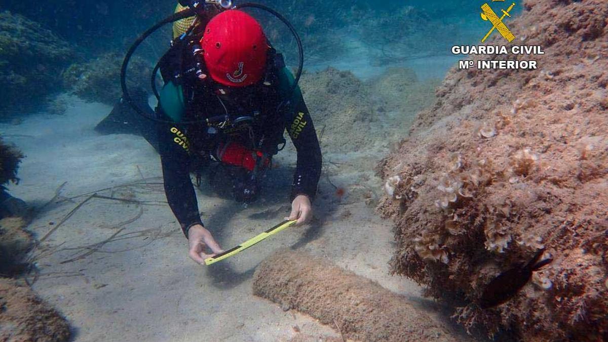 Un buceador del GEAS examina un artefacto en el mar.