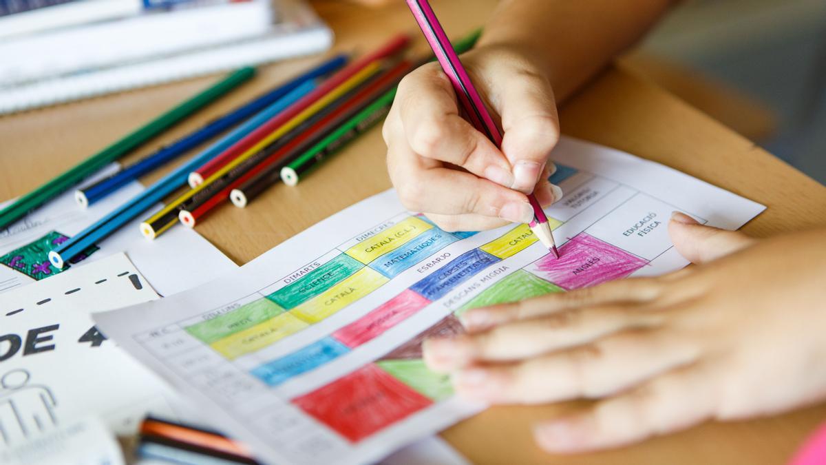 Una alumna colorea el horario del curso escolar.