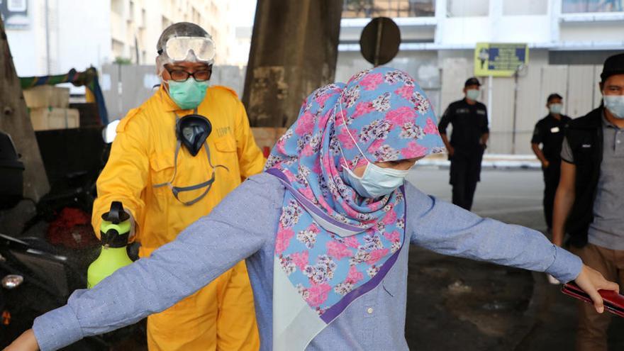 Un trabajador rocía desinfectante en una mujer durante la orden de control de movimiento debido al brote de la enfermedad del coronavirus