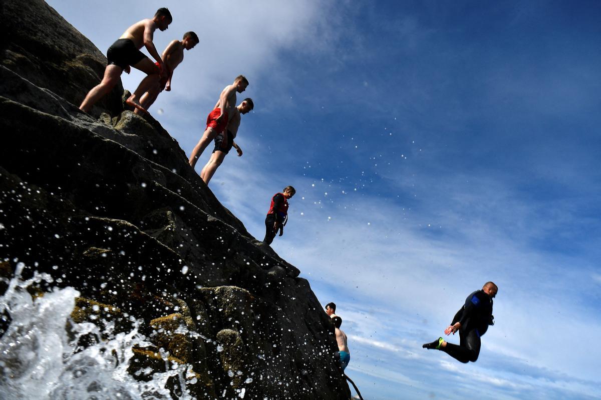 Un hombre salta al agua en el promontorio de la playa de Sandycove en Dublín, Irlanda.