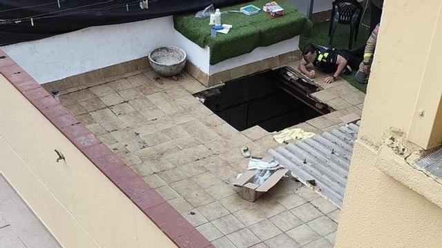 Un policia observa el forat per on va acabar caient la piscina al carrer Camcardós de Girona.