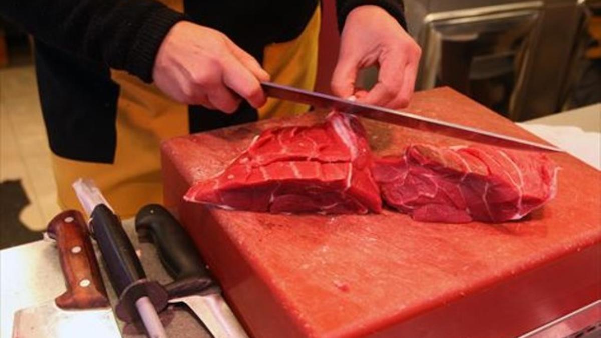 PROTEÍNAS.  Una dependienta trocea ternera en el mercado de la Guineueta.