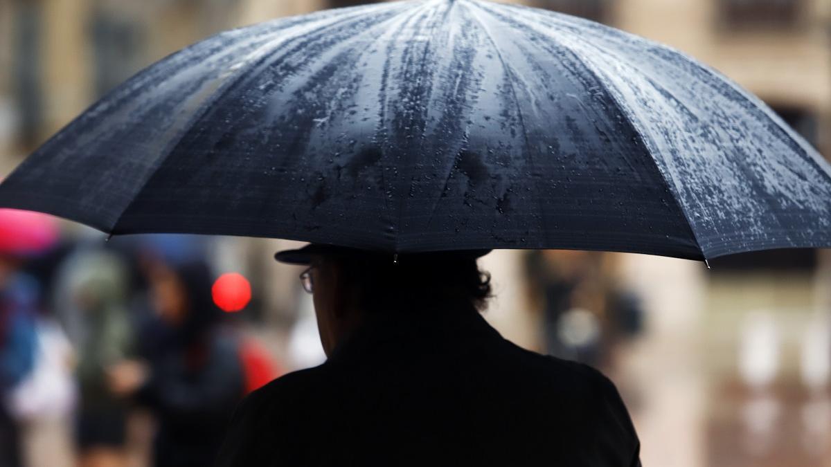Un hombre se protege de la lluvia con su paraguas en Málaga.