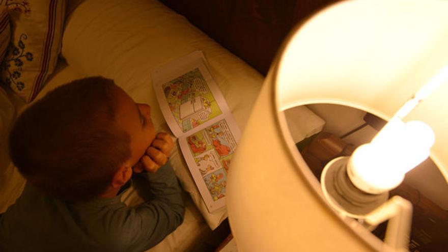 Un niño lee en su casa a la luz de una bombilla de bajo consumo // G. Santos