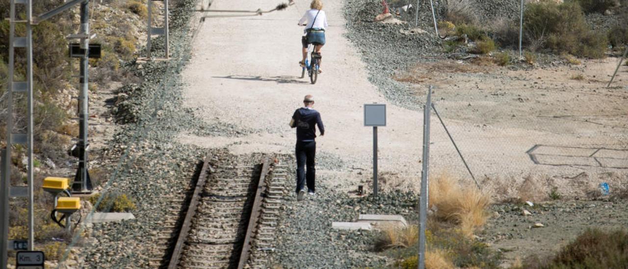 Personas pasean por el camino que ha empezado a quedar libre de las vías del tren.