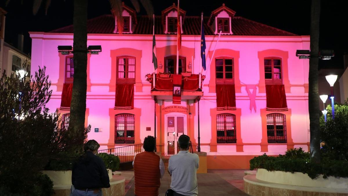 Vecinos observan la fachada iluminada en rojo de la Tenencia.