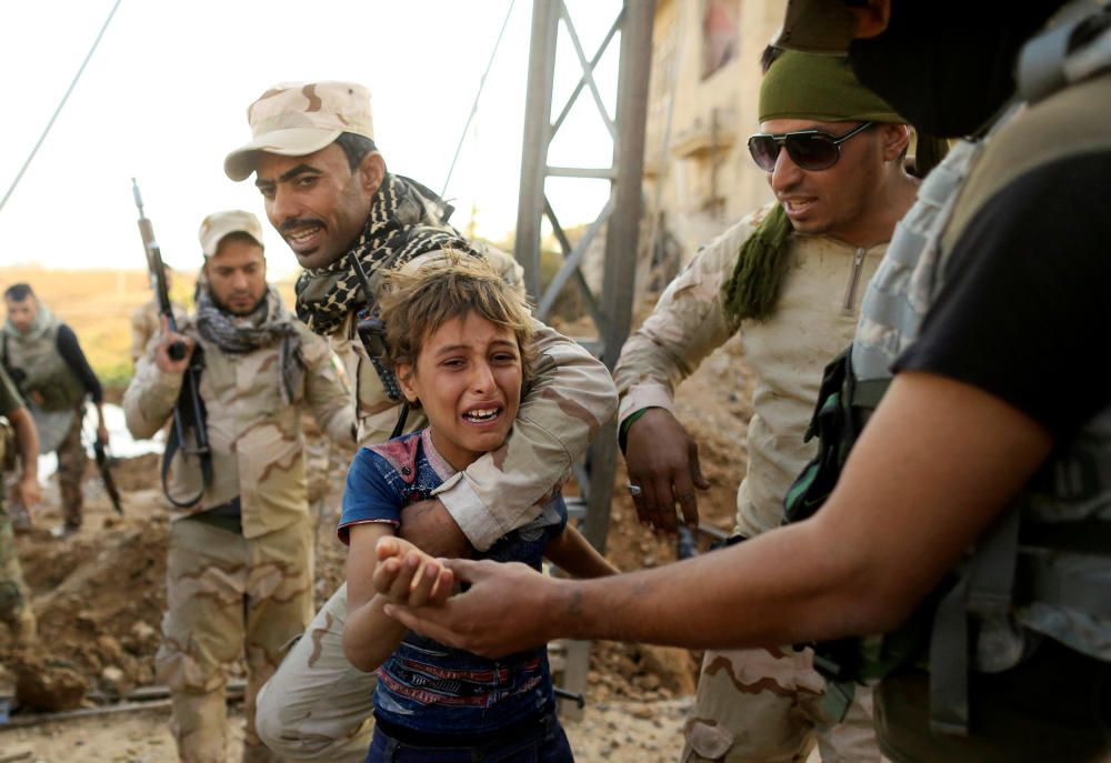 Soldados iraquíes ayudan a caminar a un niño durante la batalla contra el Estado Islámico al este de Mosul.