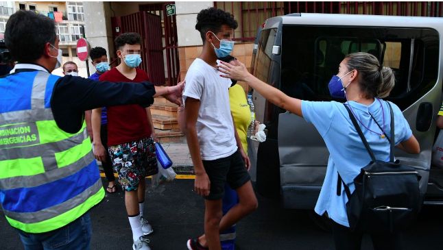 Unos trabajadores de los servicios sociales ayudan a tres de los 15 menores no acompañados marroquís que llegaron a Ceuta de forma masiva el pasado mes de mayo, el pasado día 16