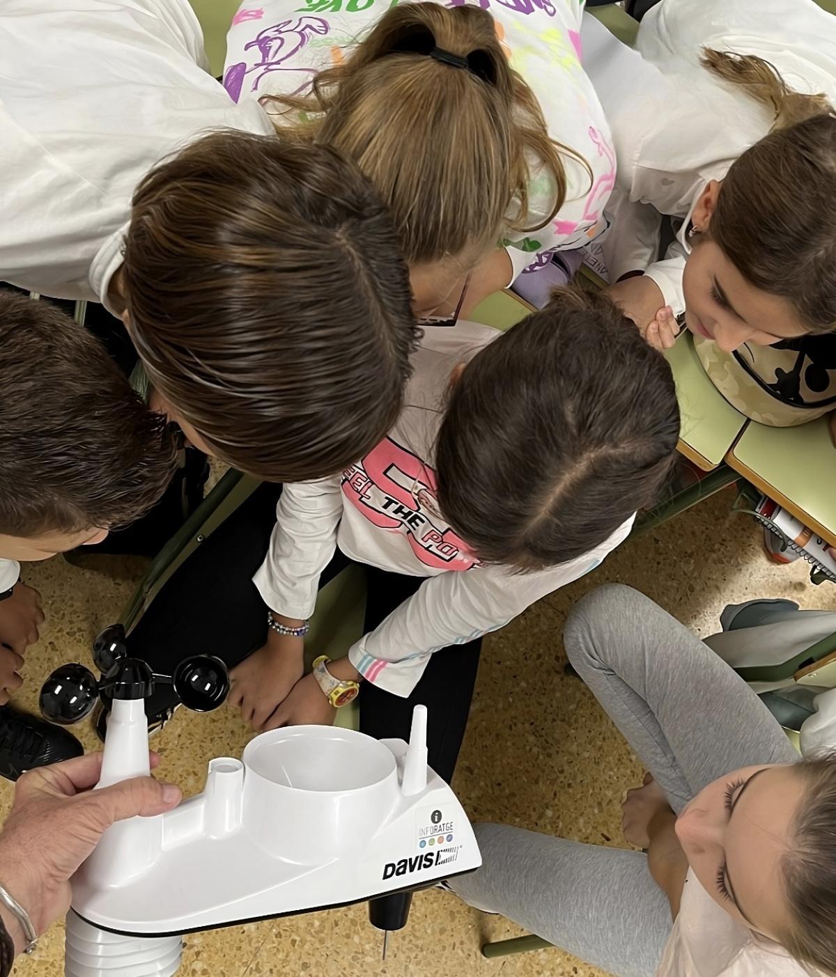 Escolars observant de prop una estació meteorològica automàtica.