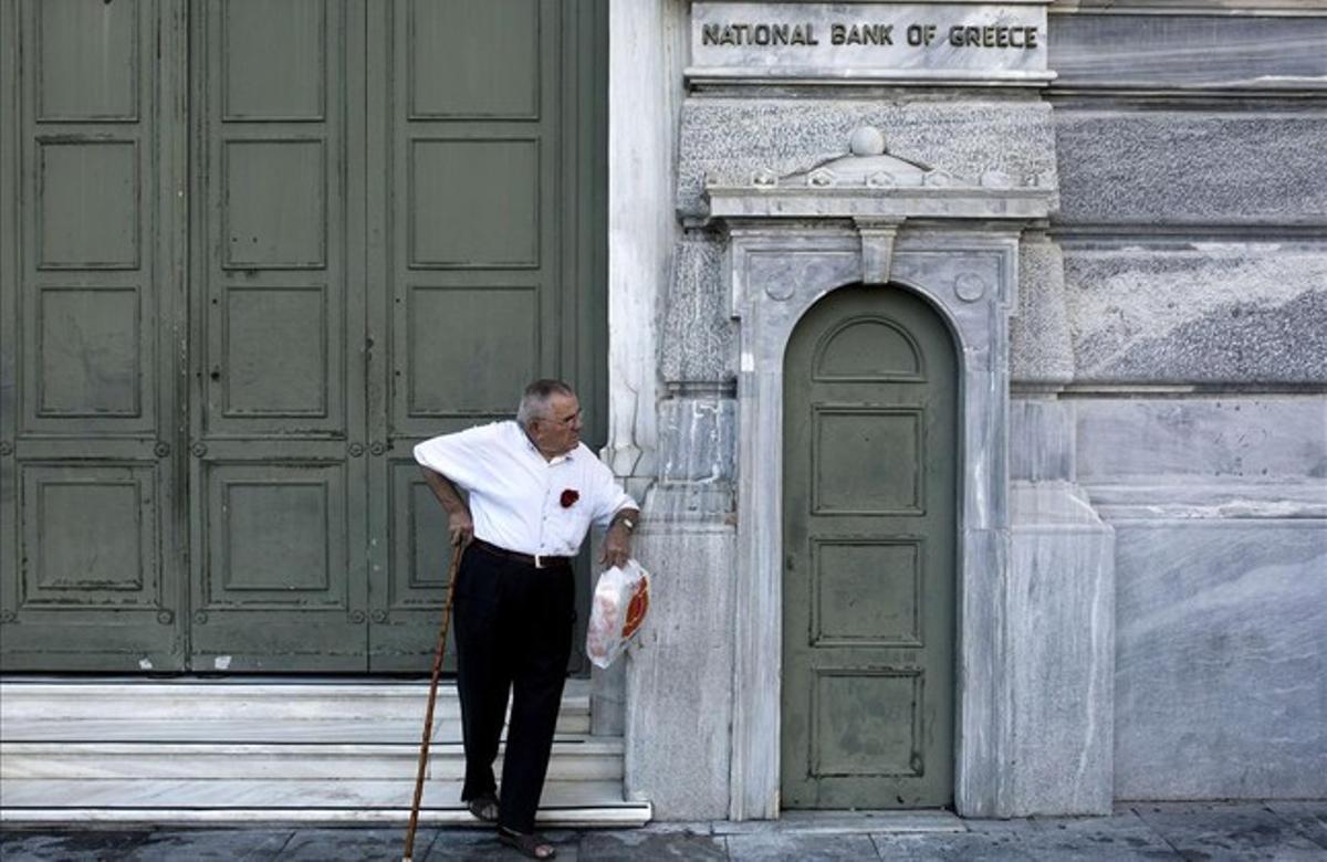 Un pensionista espera en la puerta del Banco Nacional de Grecia en Atenas.