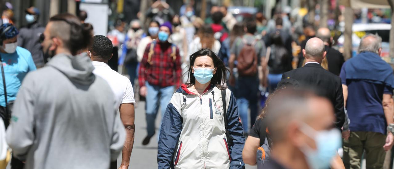 Varias personas caminan por la calle con mascarillas