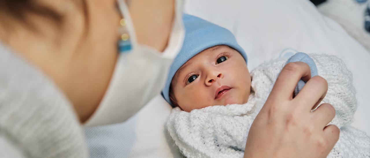 Un bebé observa a su progenitora con mascarilla