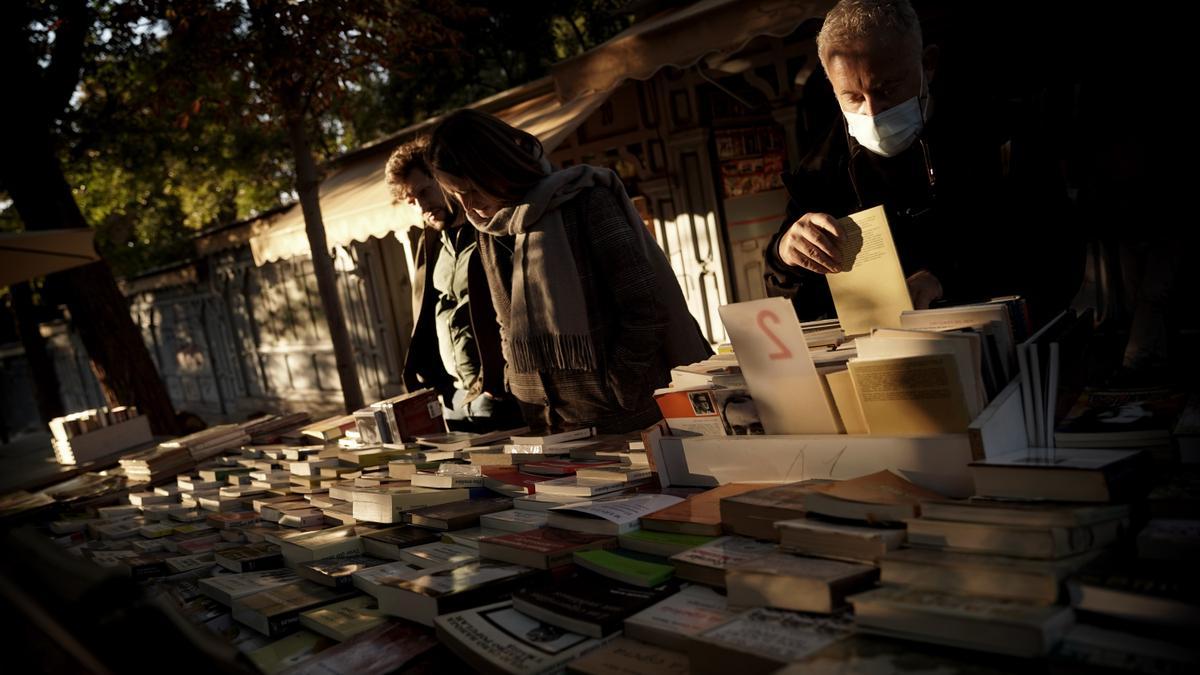 Clientes en uno de los expositores de las librerías de la cuesta de Moyano, en Madrid.